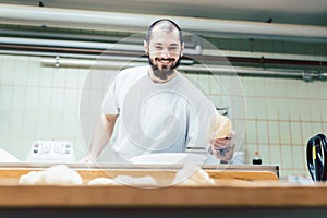 Baker with raw bread in the bakery