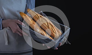 Baker`s hands hold fresh bread over dark background