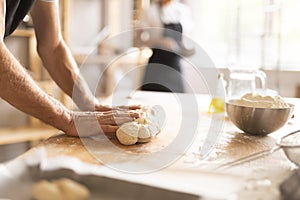 Baker's hands kneading raw dough in bakery