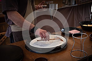 Baker`s hands pouring sweet on the griddle for the sweet crepe`s preparations photo