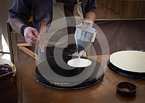 Baker`s hands pouring sweet on the griddle for the sweet crepe`s preparations photo