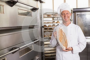 Baker showing freshly baked loaf