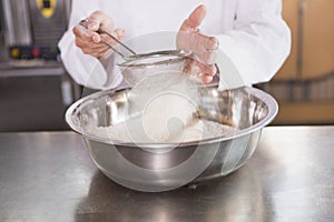 Baker sieving flour into a bowl