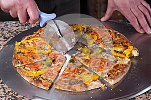 Baker Slicing Fresh Baked Vegetarian Pizza With Pizza Cutter