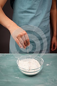 Baker sprinkle salt into the wheat flour, baking ingredient for bread, pizza or pastry dough