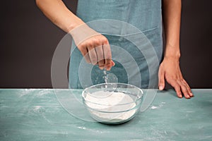 Baker sprinkles salt into a bowl with flour, prepare dough for artisan bread or pizza, ingredients for food, baking pastry