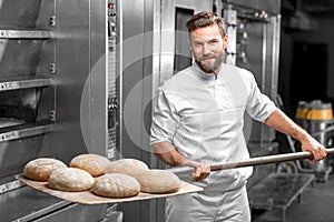 Baker taking out from the oven baked buckweat bread