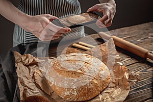 A baker is taking pictures of homemade fresh bread on his phone for a post on social networks. Baking bakery products