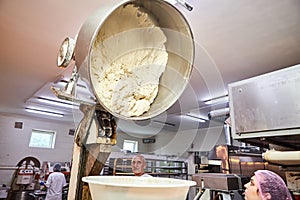 Baker team mix dough with professional kneader machine at the manufacturing. Equipment for making flour products