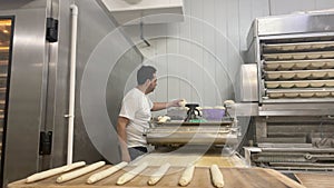 Baker weighing the dough and making loaves of bread in his small bakery. Concept baker, bread, bakery.