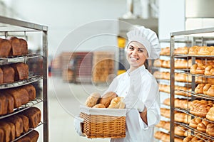 A baker woman holding a basket of baked in her hands at the bakery