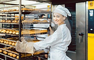 Baker woman pushing sheets with bread in the baking oven