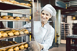 Baker woman pushing sheets with bread in the baking oven