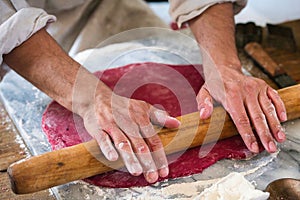 A bakers hands rolling out dough.