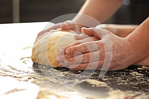 Bakers kneading dough on kitchen table