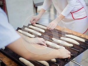 Bakers lay out the dough rolls on a baking tray