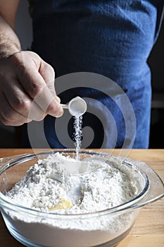 The bakers male hands add salt to the flour. Dough preparation process