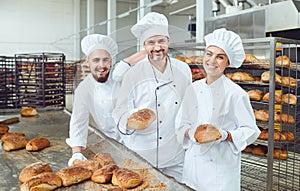Bakers smiling holding fresh bread in their hands in a bakery