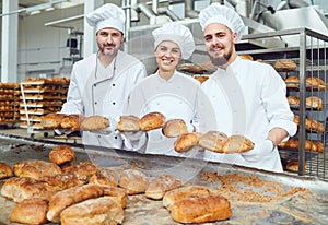 Bakers smiling holding fresh bread in their hands in a bakery