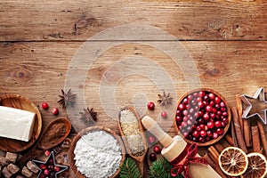 Bakery background with ingredients for cooking Christmas baking. Flour, brown sugar, butter, cranberry and spices on wooden table