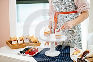 Bakery Chef decorating cupcakes with berry on the table in kitchen