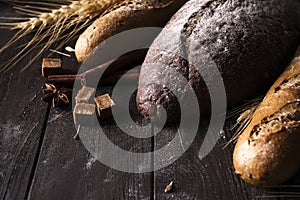 Bakery - gold rustic crusty loaves of bread and buns on black background.