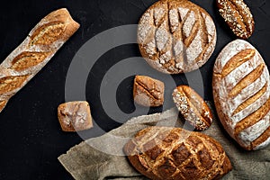 Bakery - gold rustic crusty loaves of bread and buns on black chalkboard background.