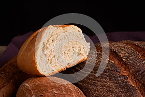 Bakery - gold rustic crusty loaves of bread and buns on black chalkboard background. Still life captured from above