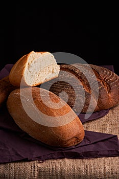 Bakery - gold rustic crusty loaves of bread and buns on black chalkboard background. Still life captured from above