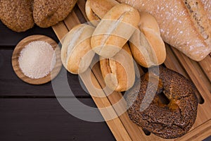 Bakery - gold rustic crusty loaves of bread and buns on black chalkboard background top view