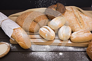 Bakery - gold rustic crusty loaves of bread and buns on black chalkboard background top view