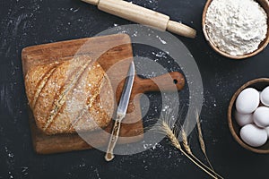 Bakery - gold rustic loaves of bread and flour on black chalkboard background.