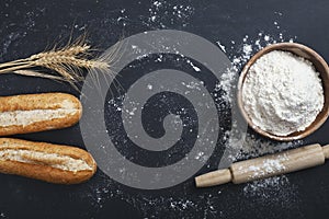 Bakery - gold rustic loaves of bread and flour on black chalkboard background.