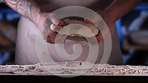 In the bakery, the hands of the baker are seen very closely as he prepares various flour products in an apron, after which he lays