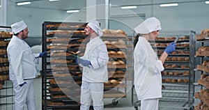 Bakery industry large video taking three bakers chatting with each other tone pretty lady baker in a white uniform