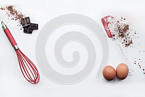 Bakery ingredients - flour, eggs, cocoa, chocolate on white table. Sweet pastry baking concept. Flat lay, copy space, top view