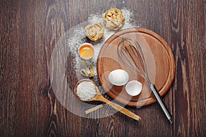 Bakery ingredients. Flour with raw eggs for dough pasta on a wooden background
