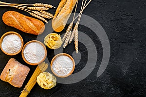 Bakery production, making bread and pasta. Fresh bread and raw pasta near flour in bowl and wheat ears on black