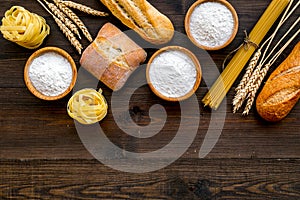 Bakery production, making bread and pasta. Fresh bread and raw pasta near flour in bowl and wheat ears on dark wooden