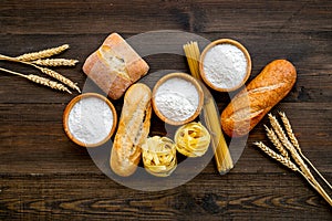 Bakery production, making bread and pasta. Fresh bread and raw pasta near flour in bowl and wheat ears on dark wooden