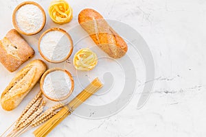 Bakery production, making bread and pasta. Fresh bread and raw pasta near flour in bowl and wheat ears on white stone