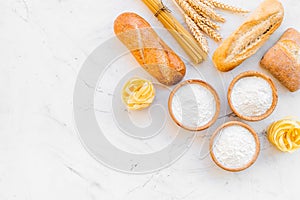 Bakery production, making bread and pasta. Fresh bread and raw pasta near flour in bowl and wheat ears on white stone