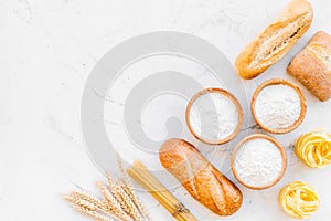 Bakery production, making bread and pasta. Fresh bread and raw pasta near flour in bowl and wheat ears on white stone