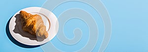 Bakery products baked croissant on white plate banner and place for advertising - Blue background, top view close-up
