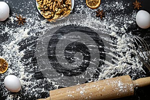 Bakery products. Cooking food ingredients: flour, eggs, nut and star anise, orange on dark table kitchen background for cake.