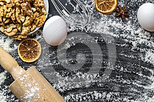 Bakery products. Cooking food ingredients: flour, eggs, nut and star anise, orange on dark table kitchen background for cake.