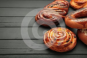 Bakery - various kinds of breadstuff. Bread rolls, bagel, sweet bun on black wooden background. Space for text