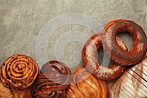 Bakery - various kinds of breadstuff. Bread rolls, bagel, sweet bun on grey background. Space for text