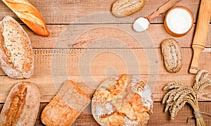 Bakery - various rustic crisp loaves of bread and rolls, wheat flour, a bunch of spikelets on wooden boards