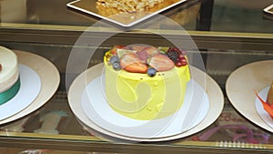 Bakery vitrine with cakes and pastries on glass shelves.